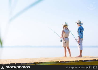 Boy and girl with fishing rods. Boy and girl with fishing rods fishing together from a pier