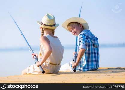 Boy and girl with fishing rods. Boy and girl with fishing rods fishing together from a pier