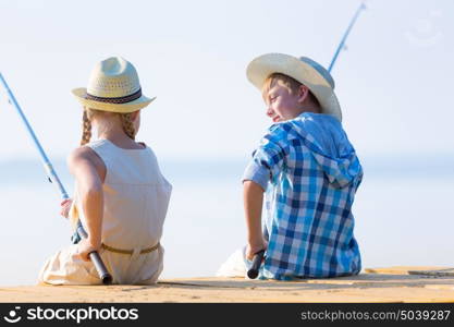 Boy and girl with fishing rods. Boy and girl with fishing rods fishing together from a pier