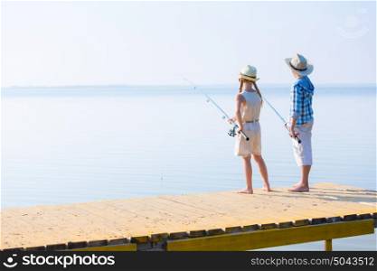 Boy and girl with fishing rods. Boy and girl with fishing rods fishing together from a pier