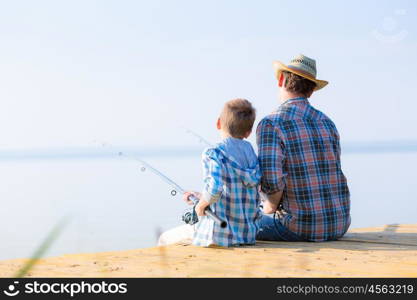 boy and his father fishing togethe. boy and his father fishing together from a pier