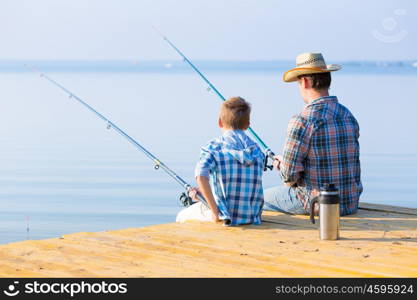 boy and his father fishing togethe. boy and his father fishing together from a pier