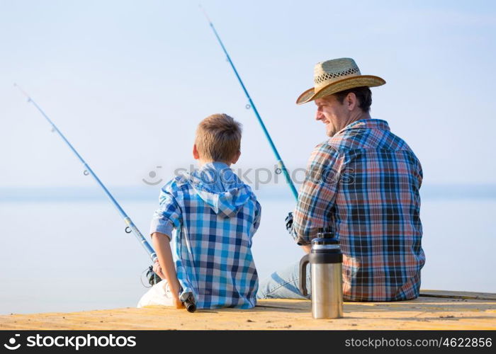 boy and his father fishing togethe. boy and his father fishing together from a pier