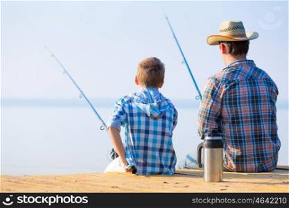boy and his father fishing togethe. boy and his father fishing together from a pier