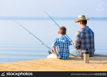 boy and his father fishing togethe. boy and his father fishing together from a pier