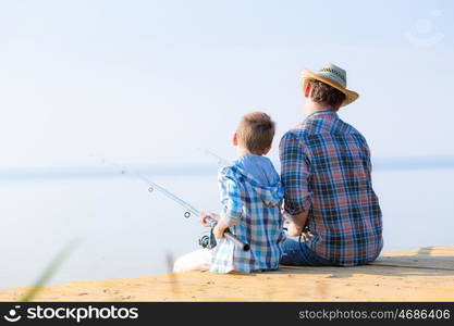 boy and his father fishing togethe. boy and his father fishing together from a pier