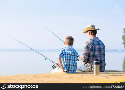 boy and his father fishing togethe. boy and his father fishing together from a pier