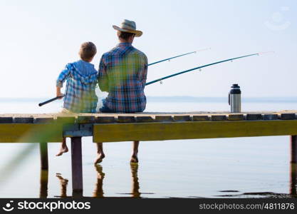 boy and his father fishing togethe. boy and his father fishing together from a pier