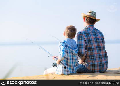 boy and his father fishing togethe. boy and his father fishing together from a pier