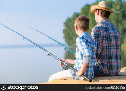 boy and his father fishing togethe. boy and his father fishing together from a pier