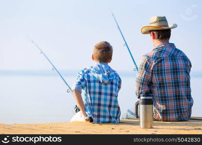 boy and his father fishing togethe. boy and his father fishing together from a pier