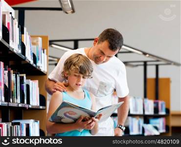 Boy and his father in library choosing books. Boy and his father in library