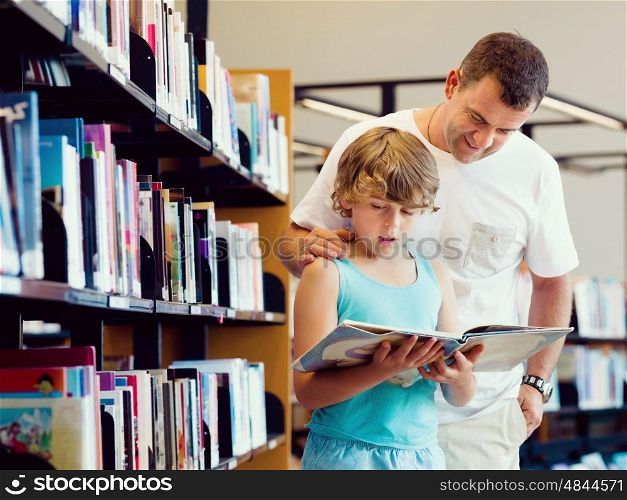 Boy and his father in library choosing books. Boy and his father in library