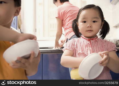 Boy and his sister helping their mother in the kitchen