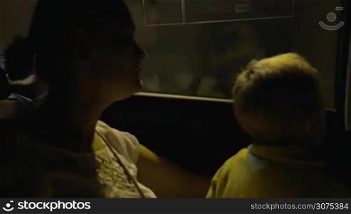 Boy and mother in the car moving through the tunnel. Woman looking out the window and then using a mobile phone