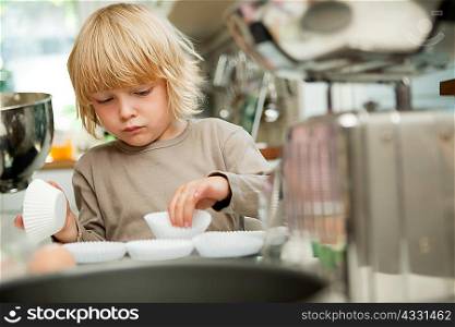 Boy arranging cake cases on baking tray