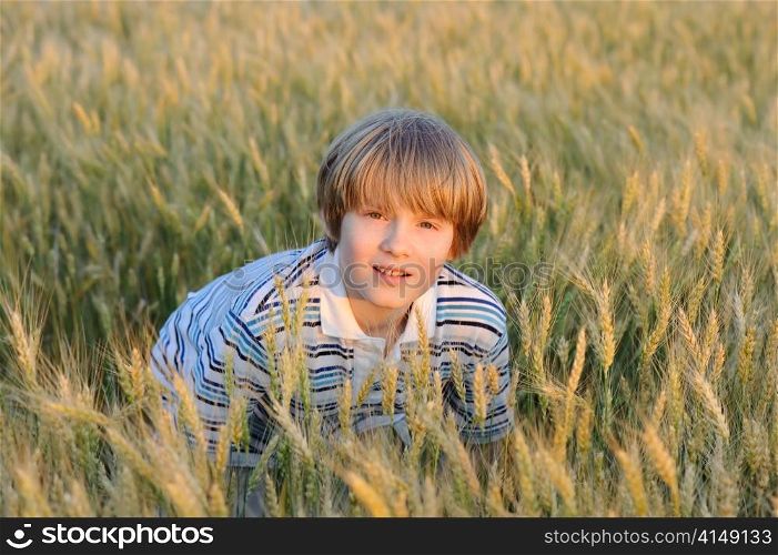boy at the wheat field illuminated by red sunset sun. boy at the wheat field
