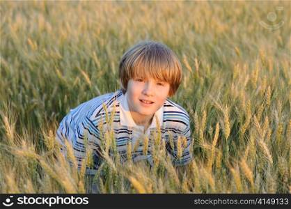 boy at the wheat field illuminated by red sunset sun. boy at the wheat field