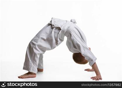 Boy athlete makes a bridge at the warm-up of the judo section