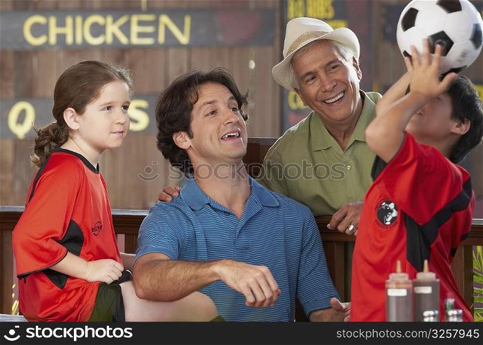 boy balancing a soccer all on his head with his family looking at him