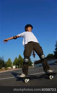 Boy balancing the skateboard shown against the blue sky
