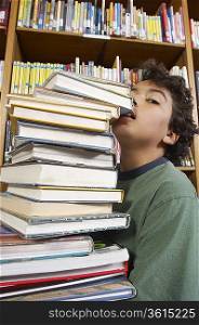 Boy carrying stack of books, close-up view