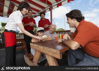 Boy celebrating his birthday with his father and grandfather in a restaurant
