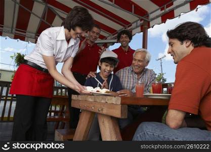 Boy celebrating his birthday with his father and grandfather in a restaurant