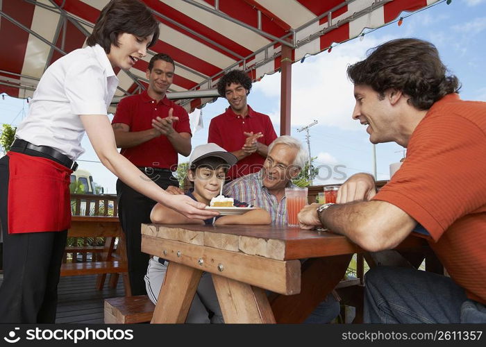 Boy celebrating his birthday with his father and grandfather in a restaurant