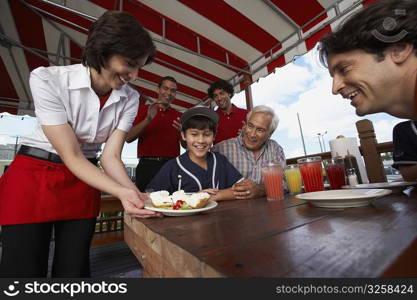 Boy celebrating his birthday with his father and grandfather in a restaurant