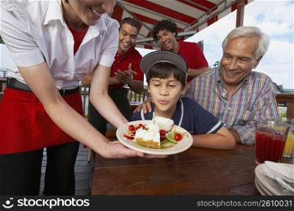Boy celebrating his birthday with his grandfather in a restaurant
