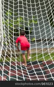 Boy climbing a rope net on the playground.