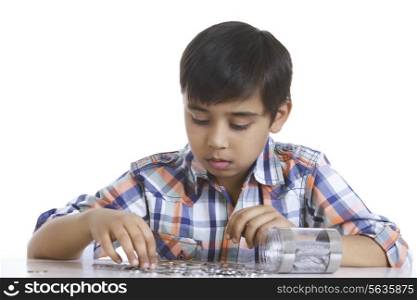 Boy counting Indian coins at table over white background