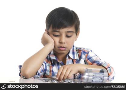 Boy counting Indian coins at table over white background