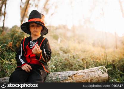 Boy disguised to halloween in the forest with blackberries in his hands