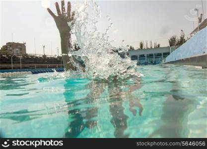 Boy dive in swimming pool and only hand over water.