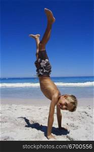Boy doing a handstand on the beach