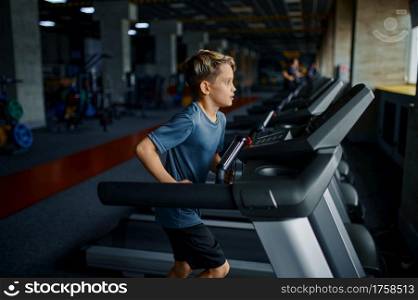 Boy doing exercise on treadmill in gym, running machine. Schoolboy on training in sport club, health care and healthy lifestyle. Boy doing exercise on treadmill, running machine