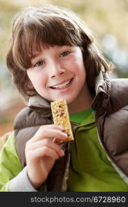 Boy Eating Healthy Snack Bar Wearing Winter Clothes