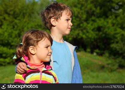 boy embraces girl for shoulder outdoor