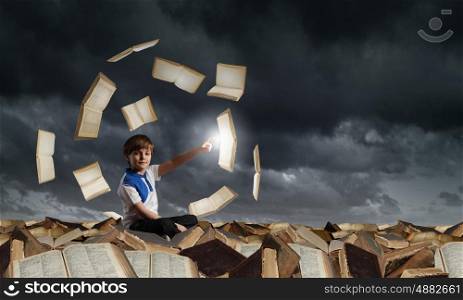 Boy exploring world. Little cute boy sitting on pile of books and pointing with finger