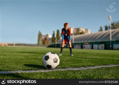 Boy football player wearing uniform looking at soccer ball before to kick training before match. Selective focus. Boy football player looking at soccer ball before to kick