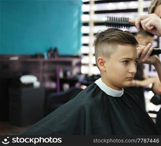 Boy getting stylish haircut in barbershop