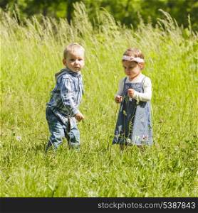 Boy gives a flower to girl. Little kids play outdoors