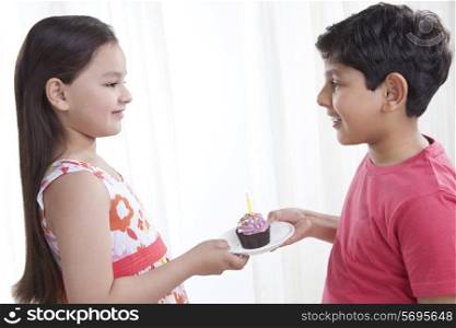 Boy giving a cupcake to a girl
