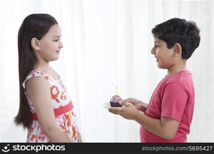 Boy giving cupcake to a girl