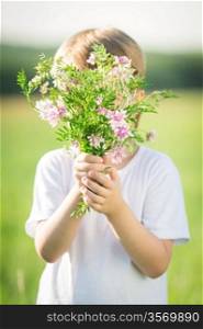 Boy hiding by bouquet of spring flowers. Mother`s day concept