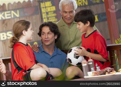 Boy holding a soccer ball with his family beside him in a restaurant