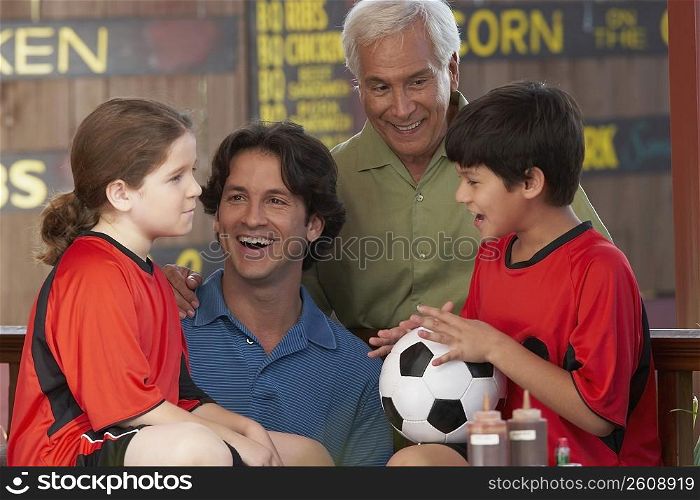 Boy holding a soccer ball with his family beside him in a restaurant
