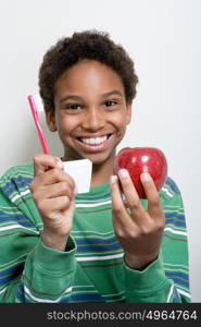 Boy holding apple and toothbrush